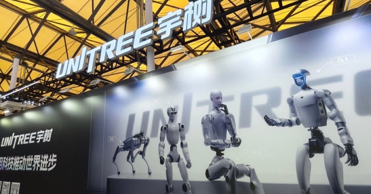A humanoid robot standing on a factory floor in China, surrounded by production equipment and manufacturing machinery.