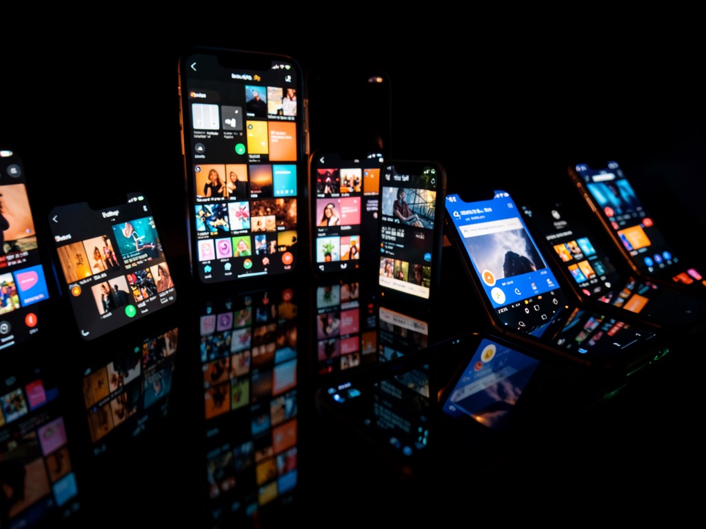 Abstract composition of phone screens glowing in a dark room, social media grids reflecting off glossy surfaces, no text no logos