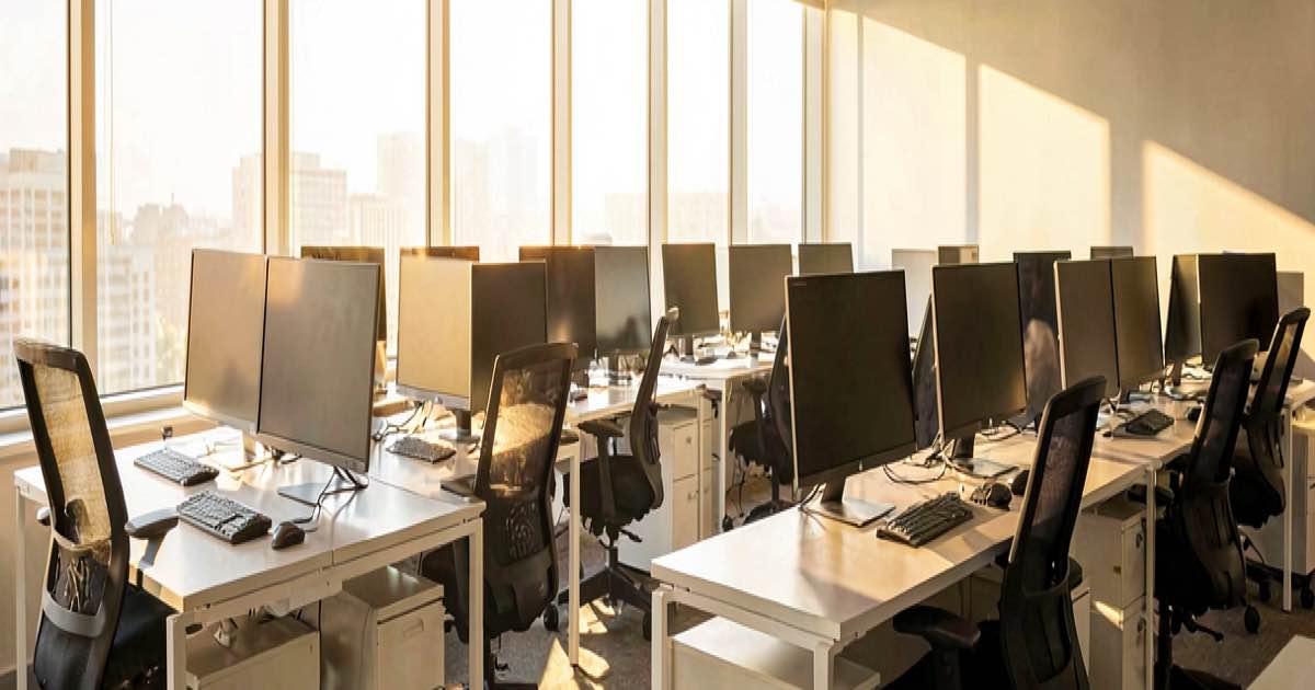 Empty office desks with computers still on, chairs pushed back, warm afternoon light through windows, documentary style