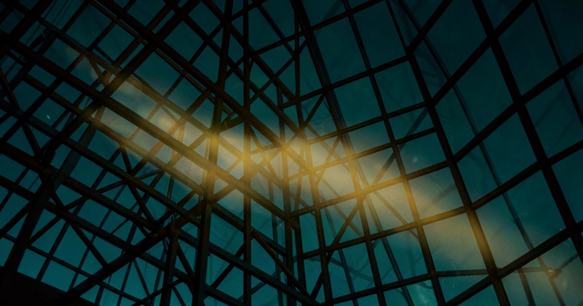 Abstract composition of golden light streaming through a dark architectural grid structure against a deep teal sky, suggesting governance and regulation in the digital age