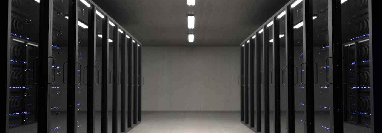A server rack in a data centre with glowing chip modules and autonomous code optimization visualisation, cold blue lighting, documentary style