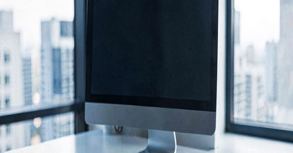 An empty office desk with a computer monitor showing a generic interface, natural lighting, editorial photography style, cool tones