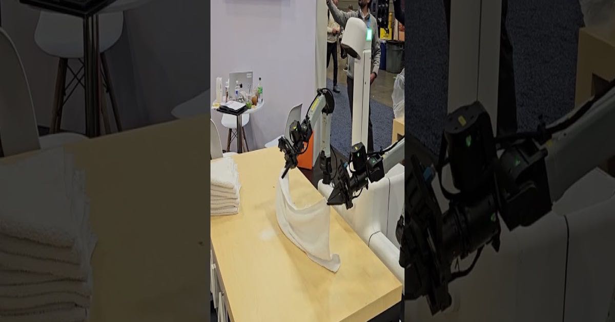 A Dyna robot arm performing a manipulation task at a trade show, demonstrating the kind of real-world action the Dyna-2 world-action model learns from human video data.