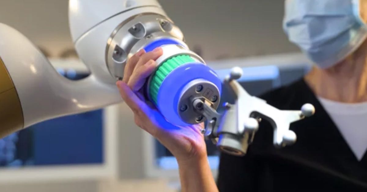 A clinician positions the eCential Robotics surgical system next to a robotic arm during bone surgery