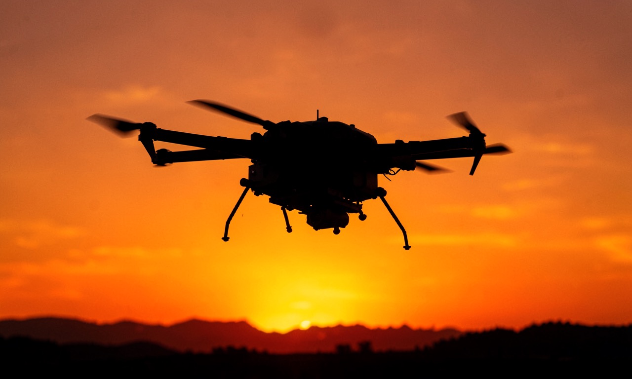 Dark silhouette of a military drone against an orange sky, representing autonomous AI warfare