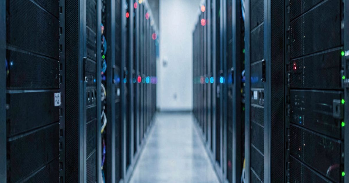 A modern data centre aisle with rows of server racks illuminated in cool blue light, representing AI inference infrastructure.