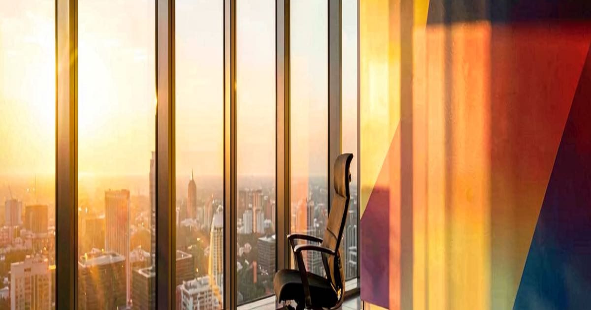 A modern office building with a Google-coloured departure sign and an empty executive chair, warm afternoon light through floor-to-ceiling windows.