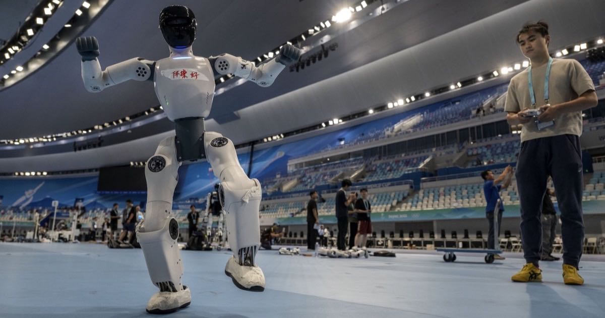 A technician controls a humanoid robot as it dances during training for the World Humanoid Robot Games at the National Speed Skating Oval, Beijing, August 2026.