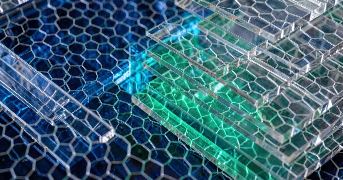 Abstract microscopic view of layered semiconductor structures in deep blue and silver with green-cyan glow between layers.