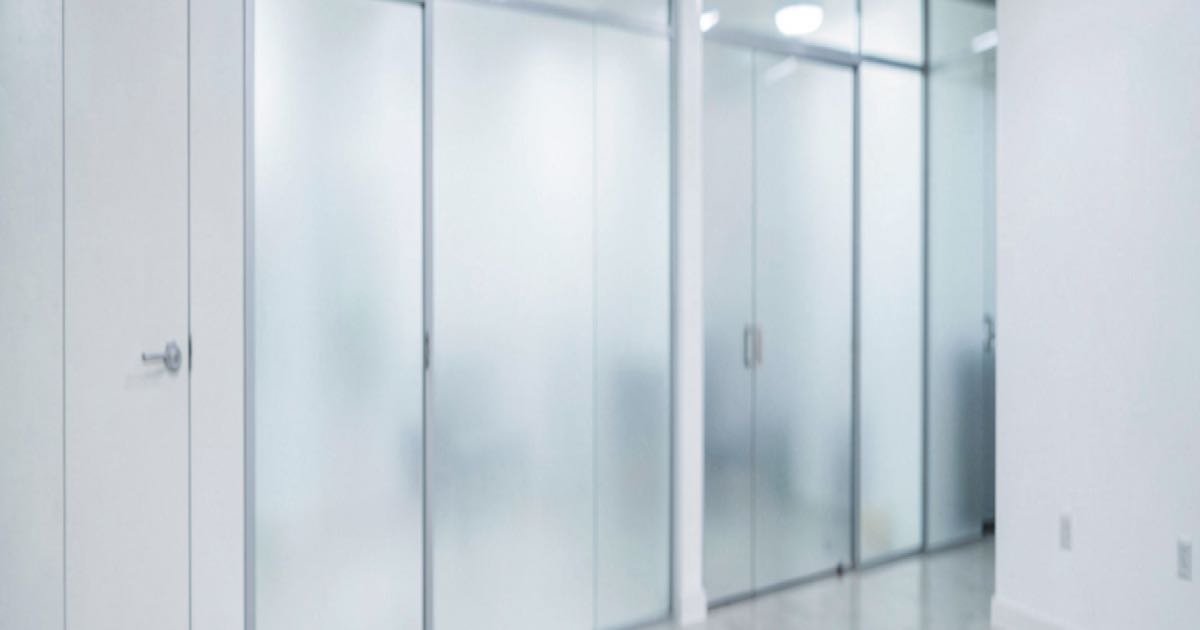 A pristine modern office lobby with frosted glass doors and no identifying signage, cold fluorescent lighting, editorial photography, minimalist