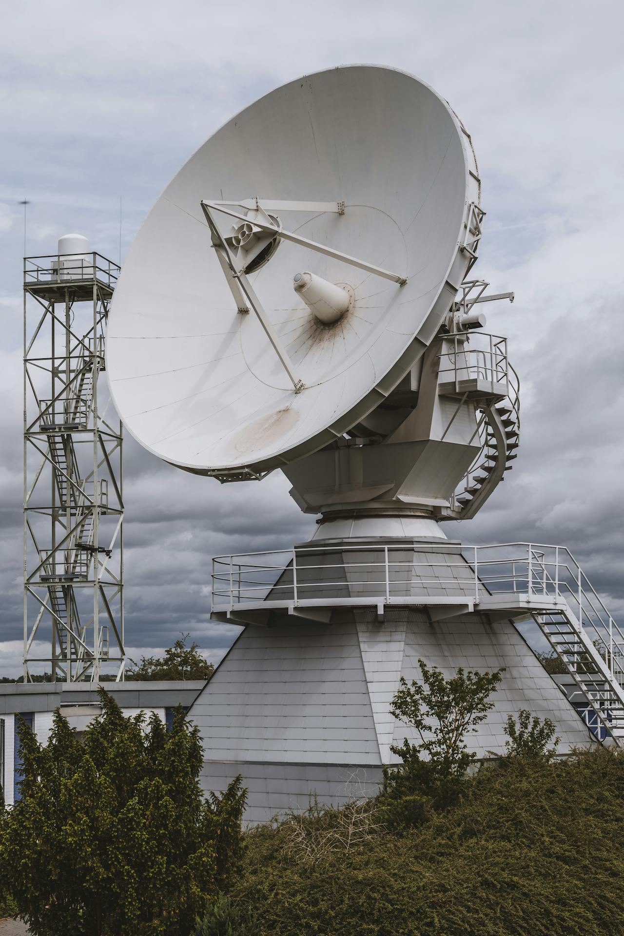 A government building at dusk with satellite dishes on the roof and a faint glow from server room windows, photojournalistic, muted colours