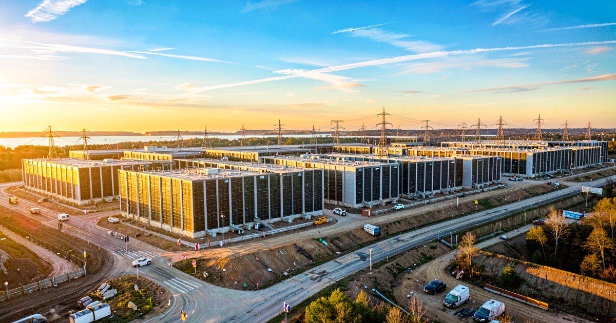 A vast data centre complex under construction on the Ohio landscape at golden hour, with rows of server buildings and power transmission lines stretching to the horizon.