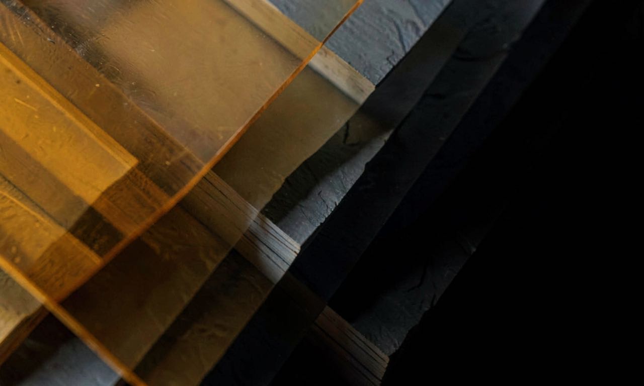 An abstract composition of layered translucent panels in amber and slate grey, suggesting stacked records fading into darkness
