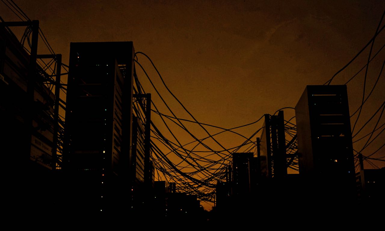 An abstract dark composition with server rack silhouettes and flowing data connections against a deep amber sky.
