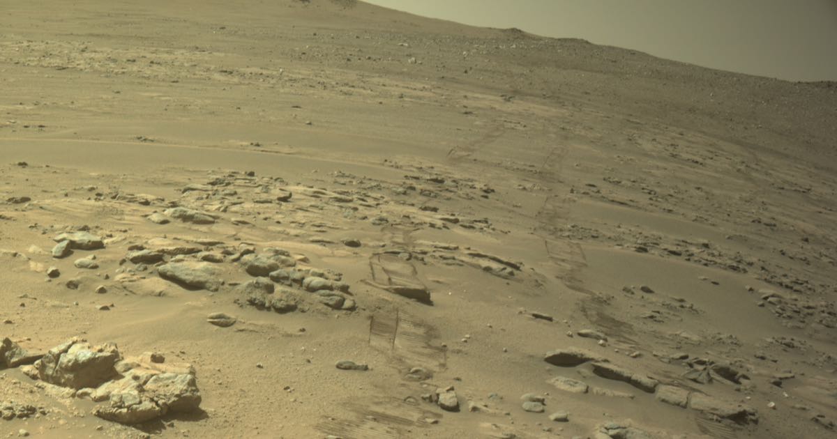 NASA's Perseverance Mars rover navcam view of rocky terrain with the rover's own wheel track visible cutting across the sand, recorded around Jezero Crater.