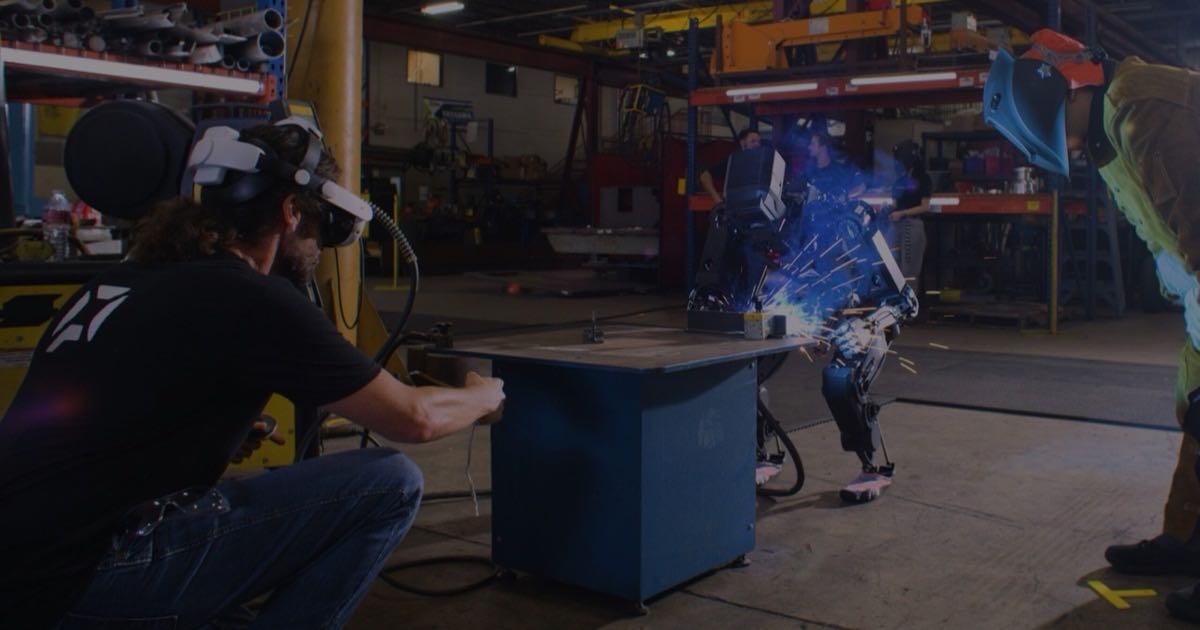 A humanoid robot performing a welding task in an industrial setting, supervised by two workers.