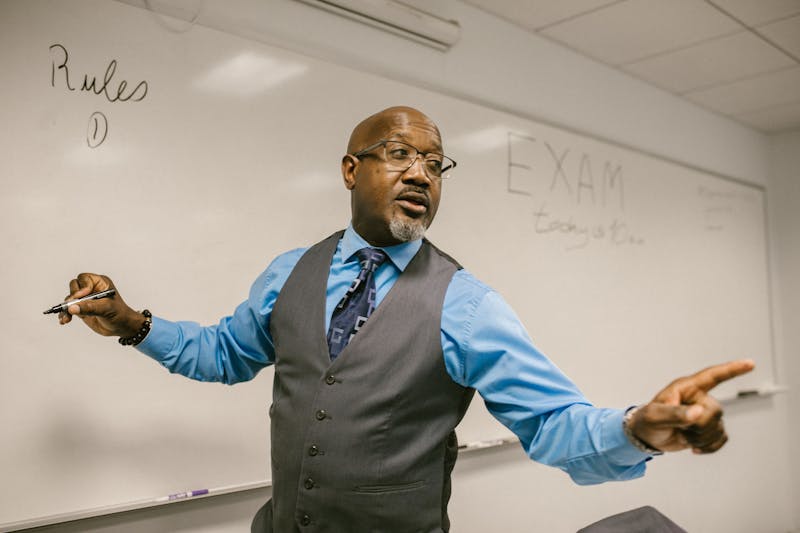 A teacher in a modern classroom using a tablet with an AI teaching assistant, warm natural light, documentary style