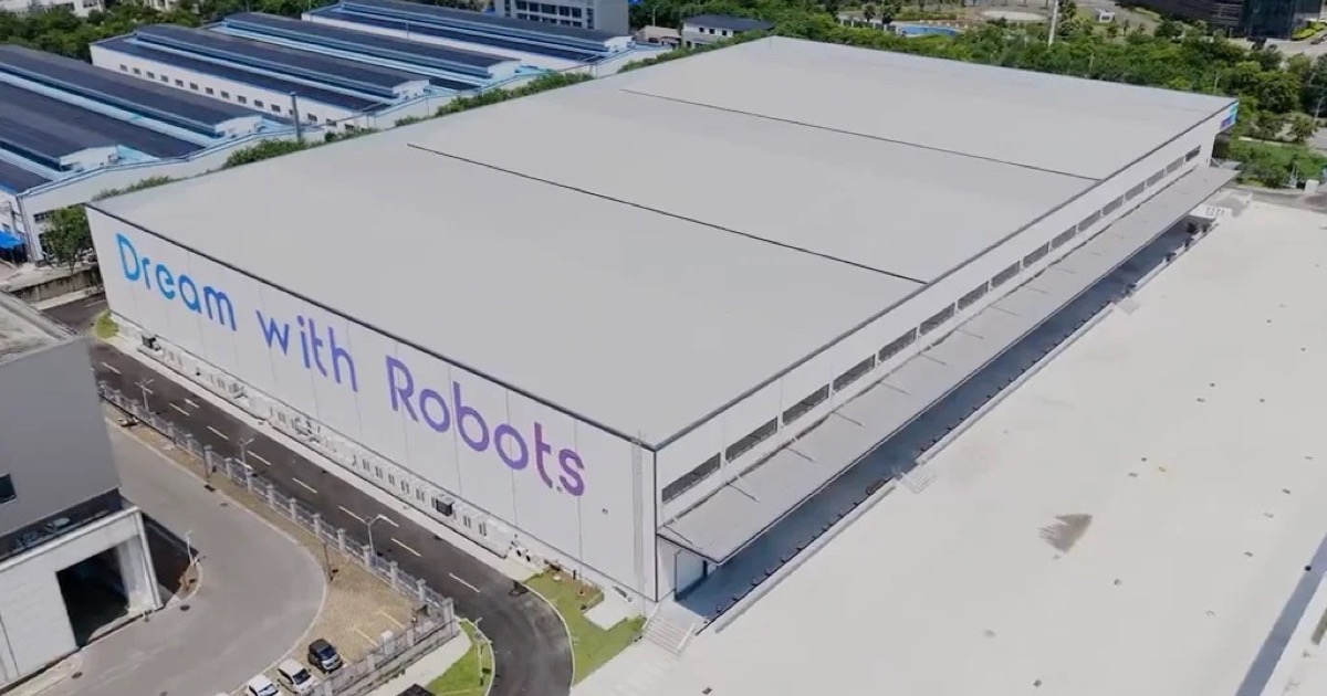 Aerial view of UBTECH's white Industrial Humanoid Robot Super Smart Factory in Liuzhou with 'Dream with Robots' painted across the roofline, surrounded by roads and greenery
