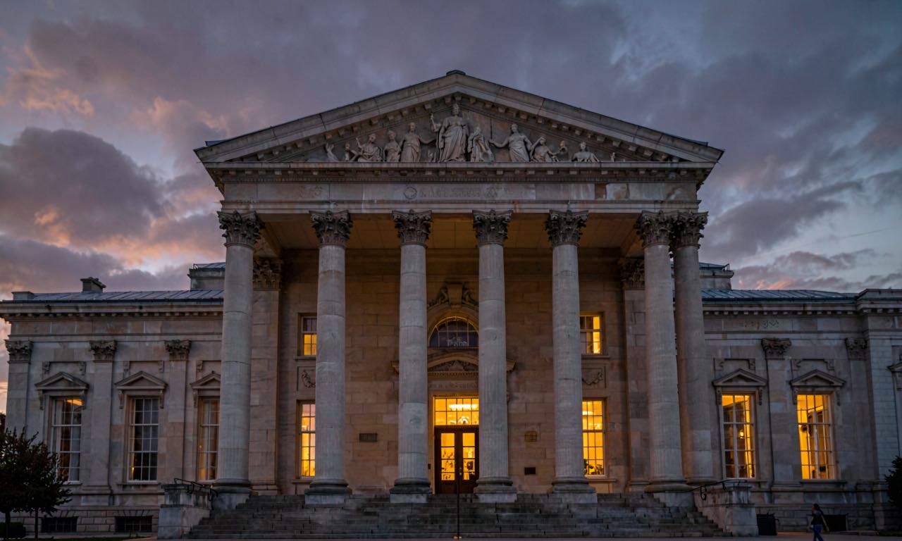 Neoclassical government building facade with columns at dusk, warm light from windows, no people, architectural detail